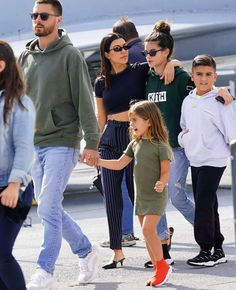 the family is walking along the tarmac with an airplane in the backgroud