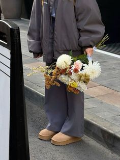 a woman is standing on the sidewalk holding flowers