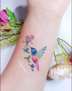 a small tattoo on the arm of a woman with flowers and birds painted on it