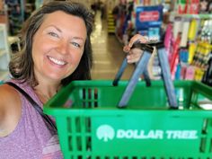 a woman is holding up a green shopping basket in a store with the dollar tree logo on it