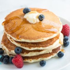 a stack of pancakes with blueberries and raspberries on top