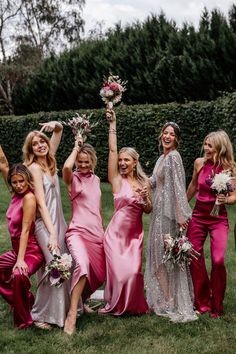 a group of women in pink dresses standing next to each other on top of a lush green field