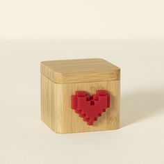 a small wooden box with a red heart on the front and bottom, sitting on a white surface