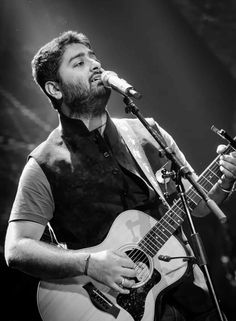 a man singing into a microphone while holding a guitar