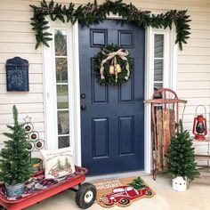 a blue front door decorated with christmas wreaths and decorations