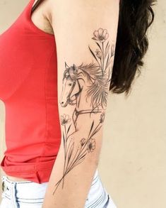 a woman with a horse tattoo on her arm and shoulder, standing in front of a wall