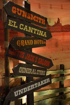 a wooden sign with many different signs on it's sides and the words gunsmth, el cantinaa, grand hotel, lets jack's saloon, general store, underneath