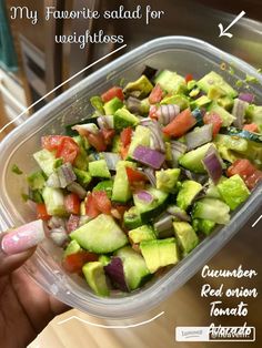 a plastic container filled with cucumber, red onion and tomato salad