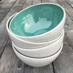 a stack of white bowls sitting on top of a wooden table