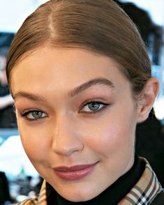 a close up of a woman with blue eyes and brown hair wearing a scarf around her neck