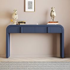 a blue console table with two statues on top and a framed photograph above it in a living room