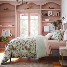 a bedroom with pink and green bedding in front of a bookcase filled with books