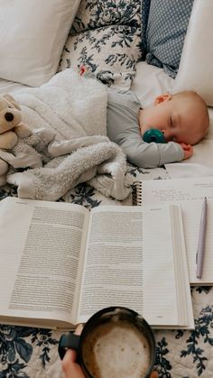 a baby sleeping on top of a bed next to an open book