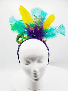 Mardi Gras headband made with purple, gold and green feathers with gold sparkle embellishments. Green masquerade mask with gold glitter detail and feathers. Headband wrapped with purple ribbon. Perfect for Mardi Gras celebration, carnival, festival or photoshoot. Green Masquerade Mask For Mardi Gras Party, Mardi Gras Costume Party Headband, Adjustable Masquerade Mask For Mardi Gras, Gold Mardi Gras Eye Mask, Mardi Gras Costume Hat With Feathers, Feathered Costume Hats And Headpieces For Mardi Gras, Feathered Hats And Headpieces For Mardi Gras Costume Party, Mardi Gras Masquerade Mask With Feathers For Party, Gold Costume Accessories For Mardi Gras Carnival