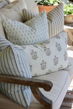 several pillows are stacked on top of each other in front of a table with potted plants