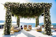 an outdoor seating area with white flowers and greenery on the side of the water