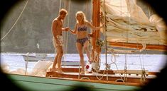 two people standing on the deck of a sailboat