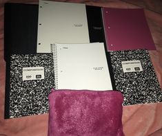 several notebooks are lined up next to each other on a pink bed sheet with black and white designs