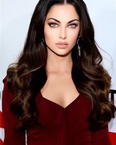 an image of a woman with long dark hair wearing earrings and red dress on the red carpet