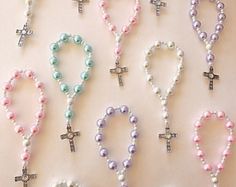 a table topped with lots of different types of beads and cross necklaces on top of each other