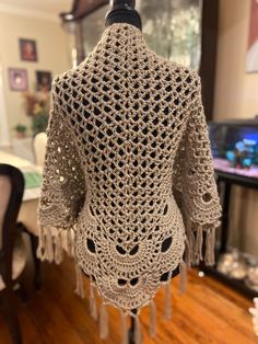 a crocheted jacket is hanging on a mannequin's head in a room