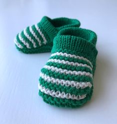 a pair of green and white knitted baby booties on top of a table