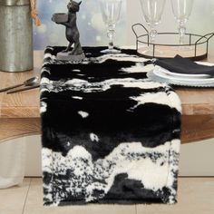 a table topped with a black and white cow print runner