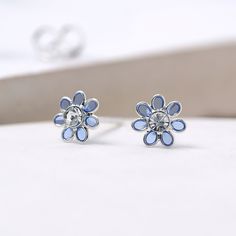 A stunning pair of tiny blue flower stud earrings with a sparkling cubic zirconia in the centre Our lovely little flower earrings are crafted from the finest sterling silver with translucent blue enamel petals and are perfect for bringing a touch of spring to your look. These dainty silver flower earrings feature a classic butterfly and post fastening and are suitable for almost any age. A lovely Christmas gift, stocking filler or for a birthday treat. A wonderfully thoughtful way to mark a mile Blue Sterling Silver Earrings With Flower Charm, Blue Flower-shaped Sterling Silver Earrings, Nickel-free Blue Sterling Silver Flower Earrings, Blue Sterling Silver Flower Earrings Nickel Free, Blue Sterling Silver Flower Earrings, Dainty Blue Flower Earrings, Blue Flower Sterling Silver Earrings, Blue Dainty Hypoallergenic Flower Earrings, Blue Flower Earrings For Mother's Day