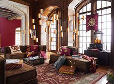 a living room filled with lots of furniture next to large window covered in red curtains