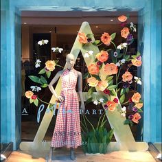 a mannequin is standing in front of a window with flowers and letters on it