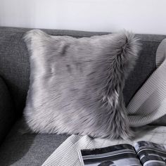 a gray couch with a book on top of it and a pillow next to it