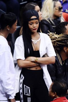 a woman standing in front of a crowd with her arms crossed and looking at her cell phone