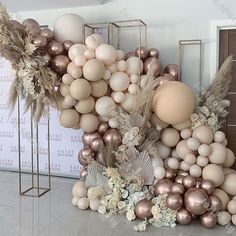 an arrangement of balloons, flowers and feathers on display in front of a large wall