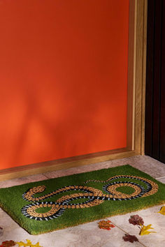 a green door mat sitting in front of an orange wall