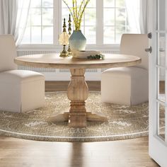 a dining room table with white chairs and a vase filled with flowers on top of it