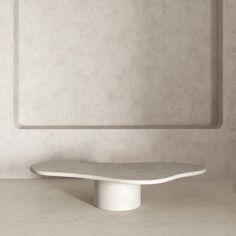 a white table sitting on top of a cement floor next to a square shaped wall