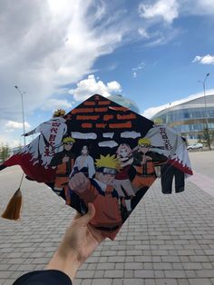 someone holding up a kite with cartoon characters on it in front of a brick walkway