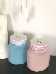 two jars sitting on top of a table next to a white frame and a blue jar