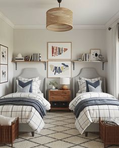 two beds in a room with pictures on the wall and lamps hanging from the ceiling