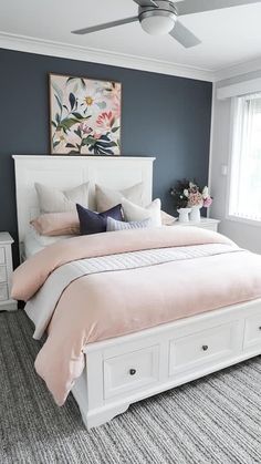 a bedroom with blue walls and white bedding, pink comforter on the headboard