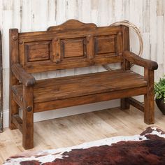 a wooden bench sitting on top of a hard wood floor next to a cowhide rug