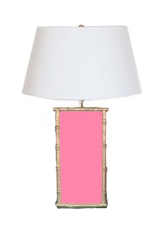 a pink table lamp with a white shade on the base and a gold bamboo frame