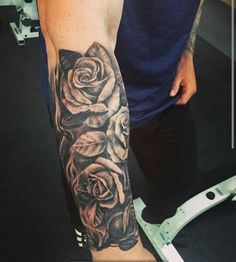 a man with a black and grey rose tattoo on his arm