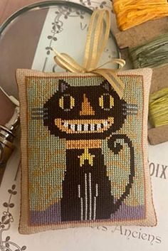 a cross stitch pillow with a black cat on it