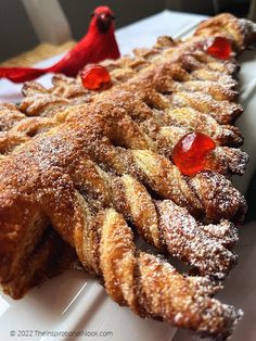 powdered sugar and jelly pastry on a white plate with a red bird sitting on top