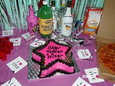 a pink cake sitting on top of a table covered in confetti and other items