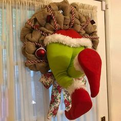 a christmas wreath hanging on the front door with an elf's hat attached to it