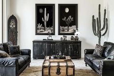 a living room with two couches and a coffee table in front of some paintings