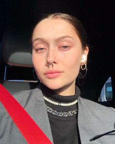 a woman with piercings on her nose sitting in a car