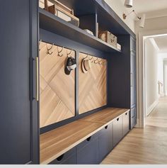 an entryway with shelves and hooks on the wall next to a wooden flooring